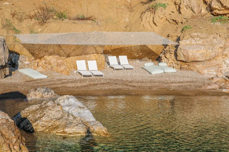 Sunbeds under a shade on the private beach, above the clear water