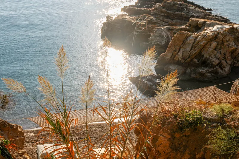 Sunlight on the sea between the rocks and the grasses