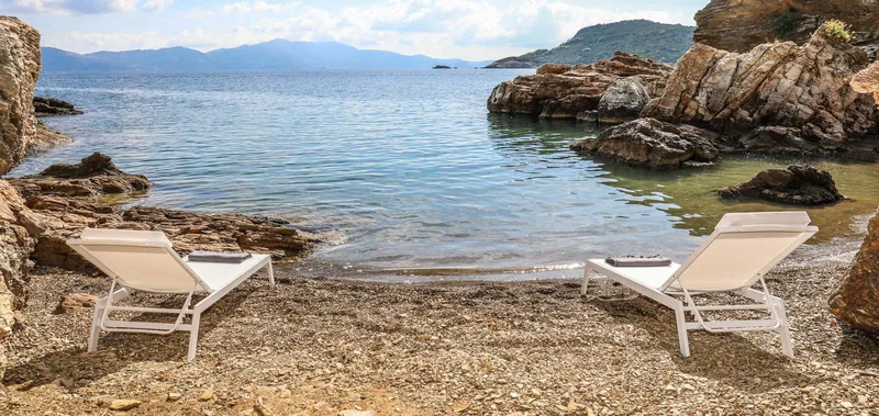 Two sunbeds on the villas’ small pebble beach, rocks and the sea around it
