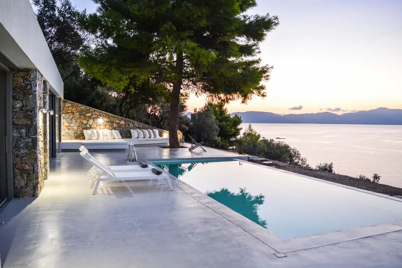 Villa Kimothoe’s infinity pool under a pine, the sea at dusk