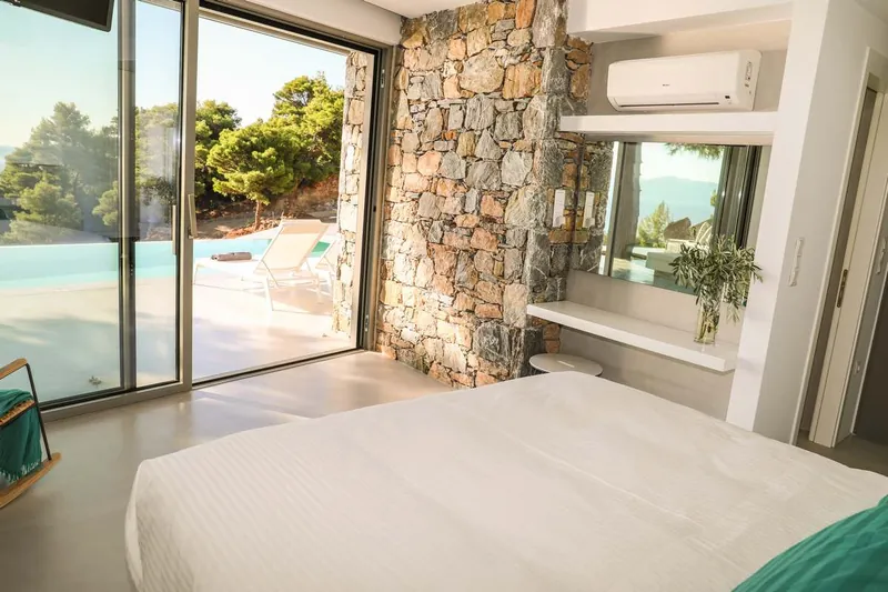 The bedroom with the stone wall and the pool beyond