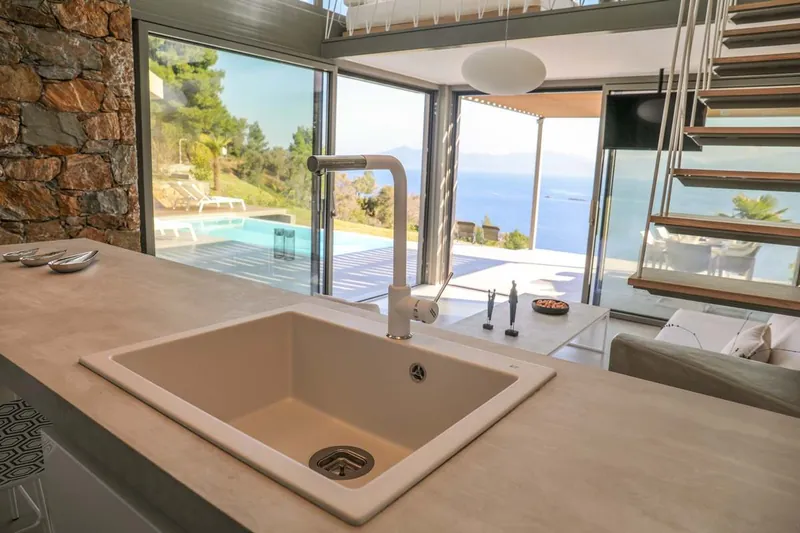 The kitchen sink with a view of the pool and the sea